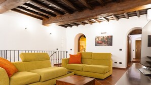 A living room with two yellow sofas, a wooden coffee table, and a TV on a dark surface. - Domus Lxvii Monti in Rome (Rome)