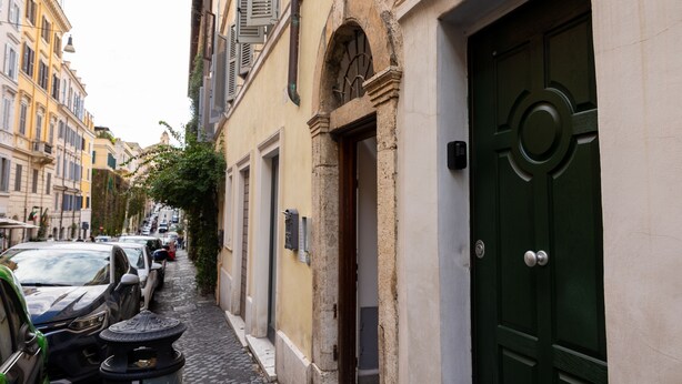 A narrow street with parked cars and a green door on the right. - Domus Lxvii Monti in Rome (Rome)