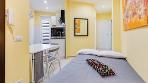 A compact hotel room with a bed, a small kitchenette, a dining area, and a bathroom. - Monteverde Cozy Apartment (Rome)