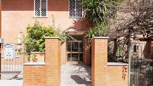 A brick building with a gated entrance, a mailbox, and a small garden area with plants. - Monteverde Cozy Apartment (Rome)