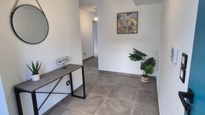 A hallway with a round mirror, a small table with a plant, and a sign that says "Take it easy".