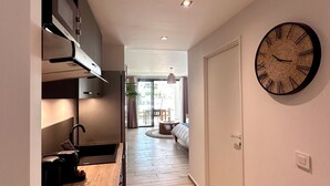A modern kitchen with a wooden countertop, built-in cabinets, and a large wall clock. - Studio Eleven Alamanda Beach beachfront (Saint Martin)