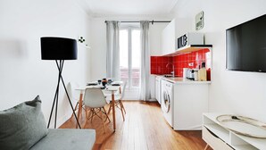 A compact living space with a dining area, kitchenette, and a TV mounted on the wall. - Cosy 1br/4p - Montmartre/sacre Coeur (Paris)