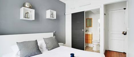 A hotel room with a large bed, grey walls, and a breakfast tray on the bed.