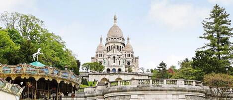 A historic building with a prominent dome and a carousel in the foreground.