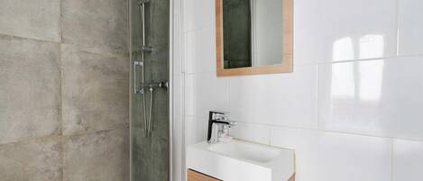 A bathroom with a glass-enclosed shower, a white sink, and a wooden cabinet.