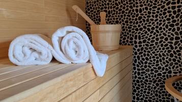 Un banco de madera con toallas y un balde de madera en un entorno de spa.