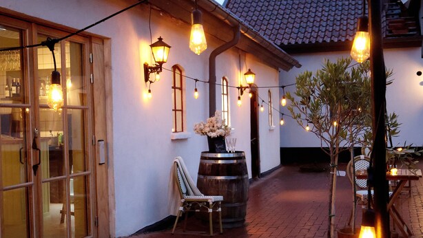 A cozy outdoor seating area with string lights, a wooden barrel, and a chair. - Fontänens Bed & Breakfast (Trelleborg)