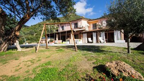 A house with a garden, a swing set, and a view of a hill. - Vacation home Cartuceddu 3b - Marina di Tertenia (TERTENIA)