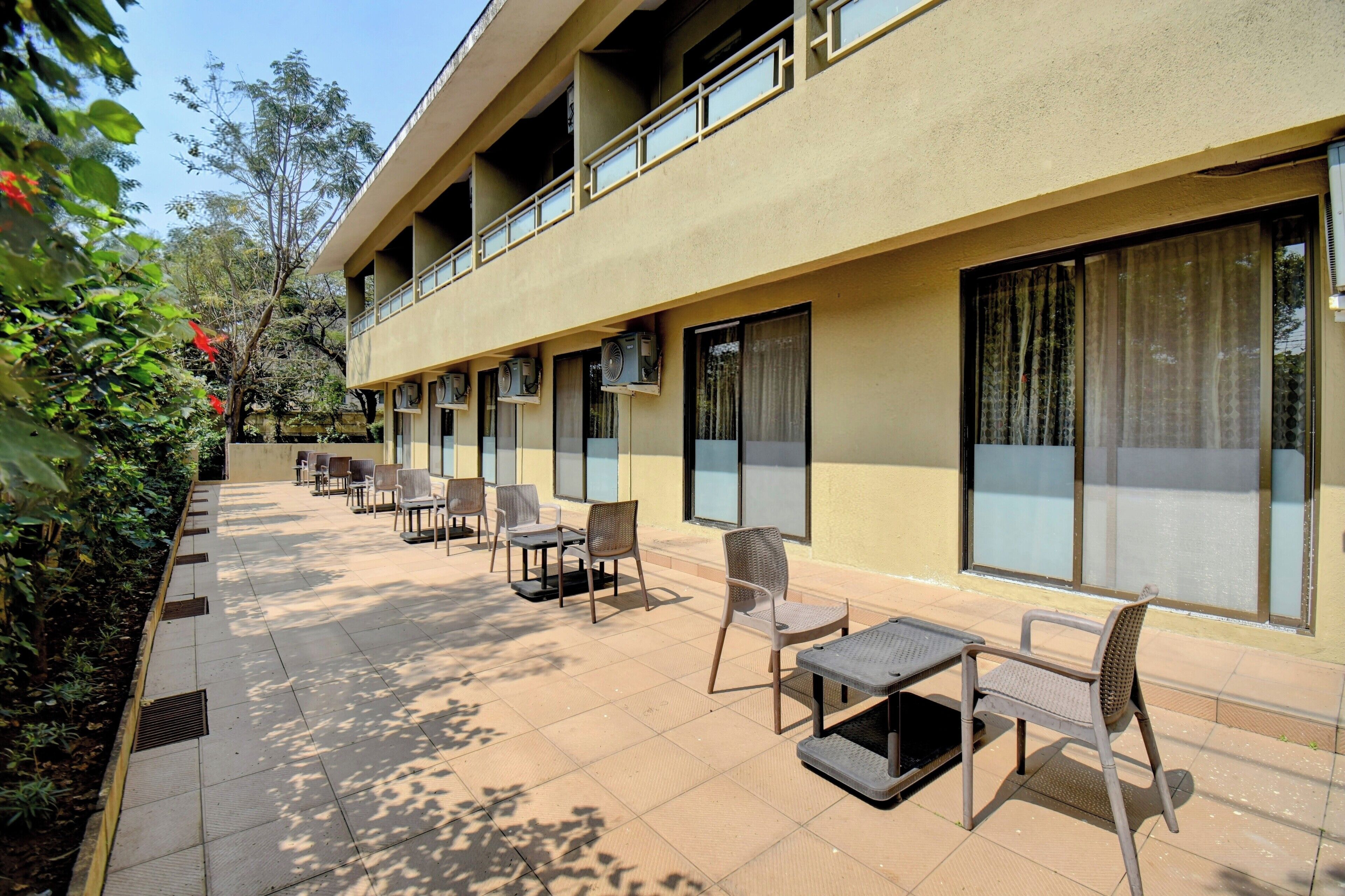 A hotel with outdoor seating, air conditioning units, and large windows.