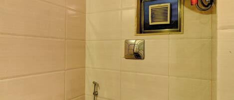 A small, clean bathroom with a toilet, a towel rack, a hand dryer, and a ventilation unit.