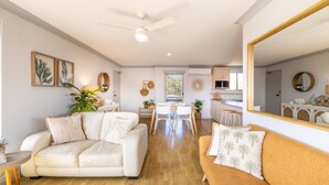 A spacious living area with a sofa, a dining table, and a kitchen in the background. - Commodore 6, 6 Intrepid Cl - water views, Air Con, Wi-Fi (Nelson Bay)