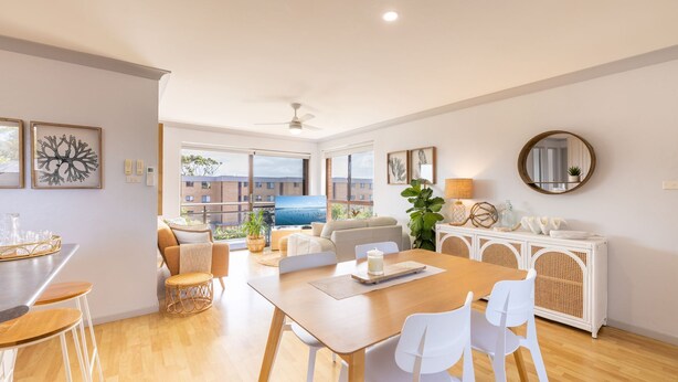 A modern living room with a dining area, large windows, and a view of the cityscape. - Commodore 6, 6 Intrepid Cl - water views, Air Con, Wi-Fi (Nelson Bay)