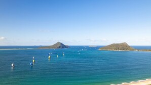 A coastal scene with clear blue waters, several sailboats, and two prominent hills in the background. - Commodore 6, 6 Intrepid Cl - water views, Air Con, Wi-Fi (Nelson Bay)