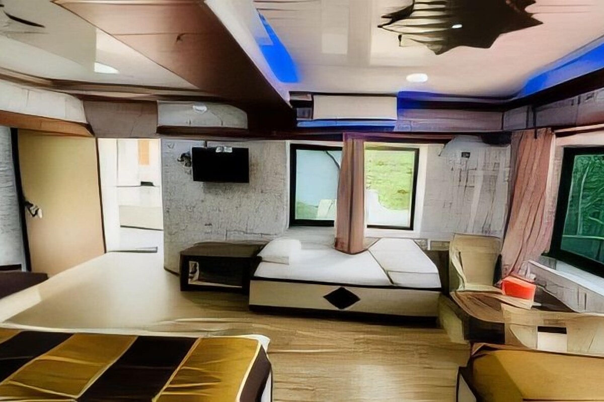 A modern interior with a bed, a desk, and a window with a view of greenery.