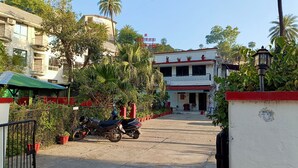 Ein Hotel mit roter und weißer Fassade, einem überdachten Parkbereich mit Motorrädern und üppiger Bepflanzung.