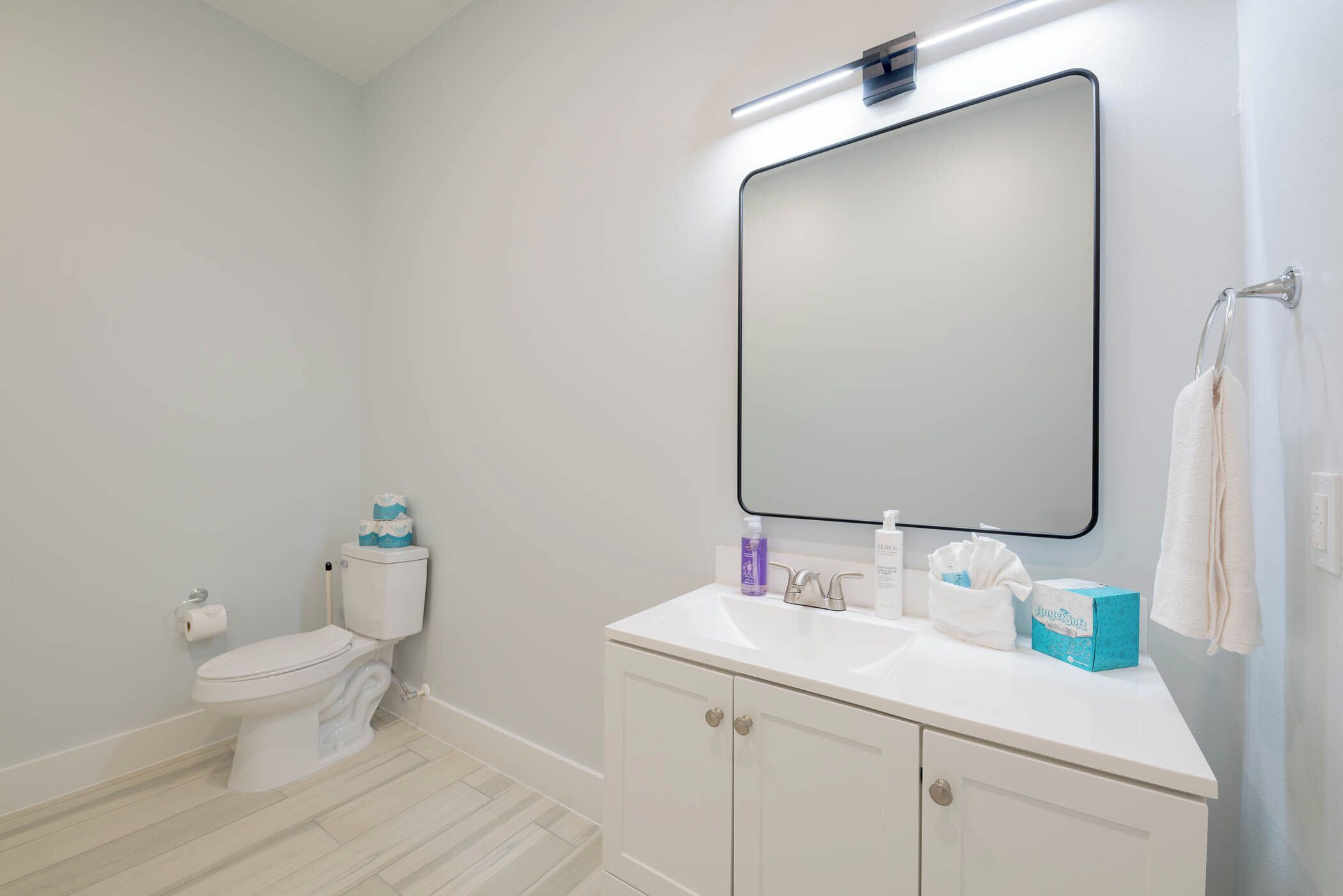 A bathroom with a toilet, sink, and mirror.