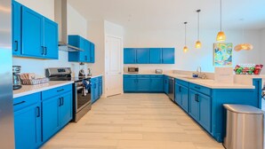 Une cuisine moderne avec des armoires bleues, des appareils en acier inoxydable et des luminaires suspendus.
