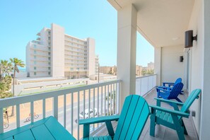 A balcony with turquoise chairs and a view of a multi-story building.