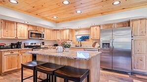 Una cucina moderna con mobili in legno, elettrodomestici in acciaio inossidabile, un'isola in marmo e un forno integrato.