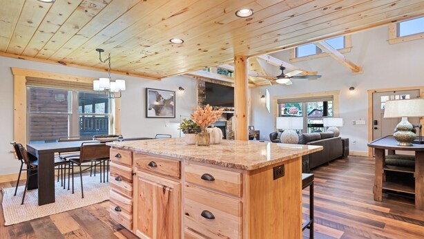 Un'ampia cucina con una grande isola, soffitto in legno ed elettrodomestici integrati.