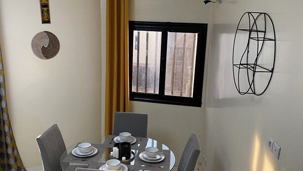 Ein Essbereich mit einem runden Tisch, sechs Stühlen und einem Fenster mit Vorhängen.