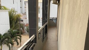 Ein schmaler Balkon mit Blick auf umliegende Gebäude und eine Palme.