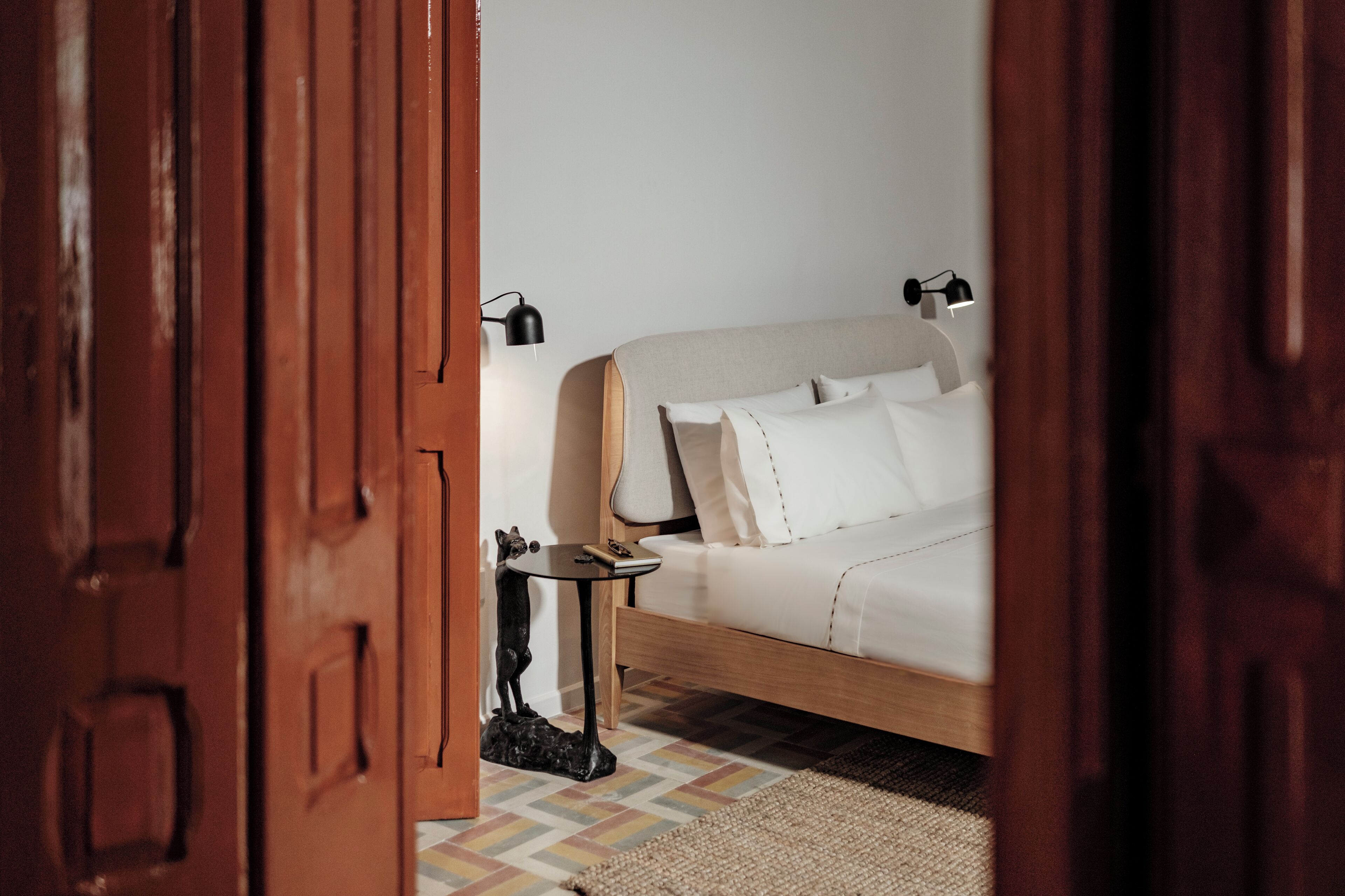 Una camera da letto con un letto, lampade da comodino, un tavolino e un tappeto.