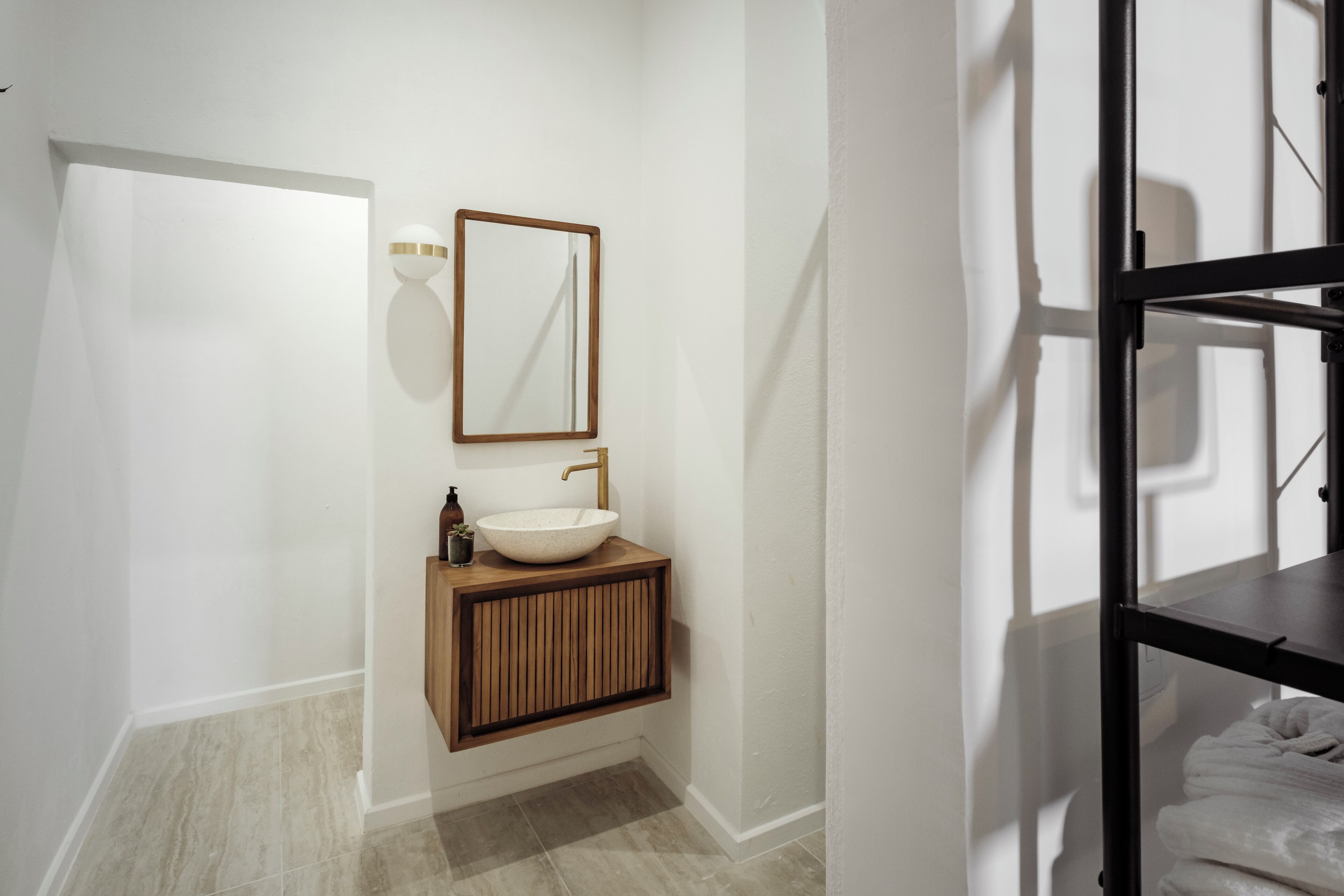 Un baño moderno con tocador de madera, un espejo grande y un lavabo blanco.