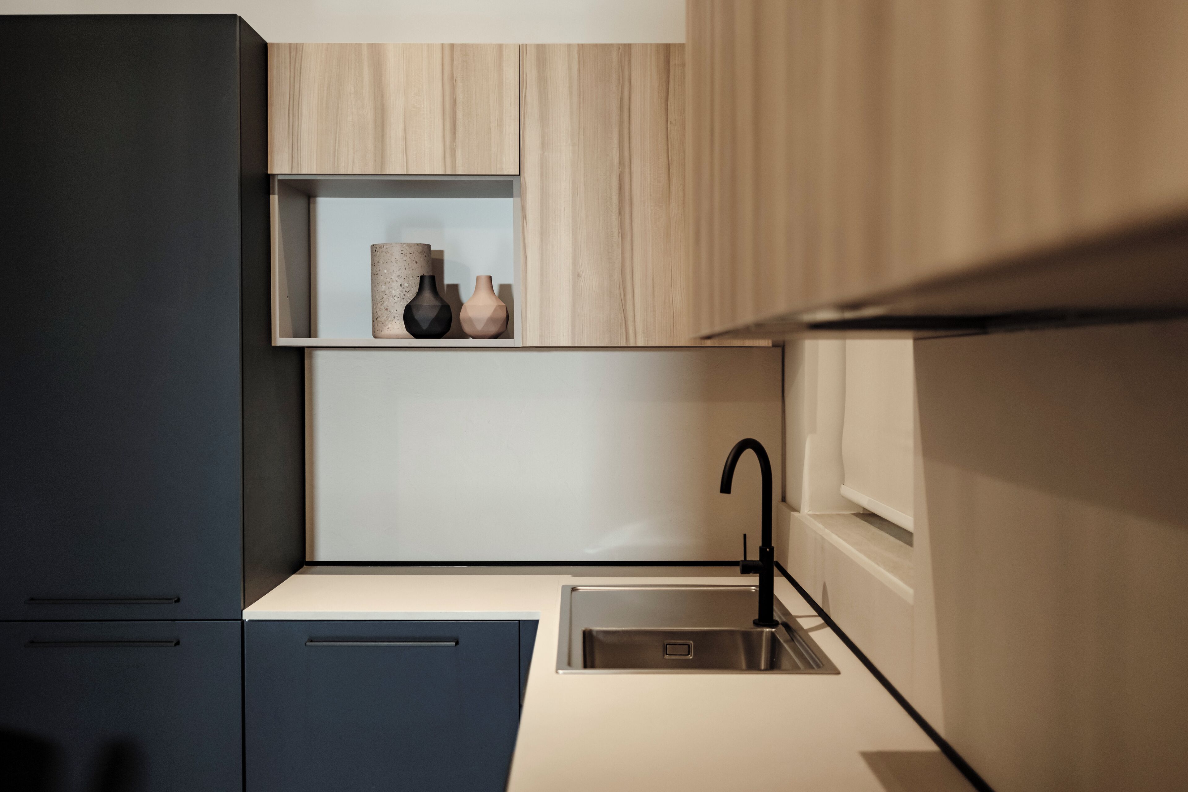 Une cuisine moderne dotée d’un évier encastré, de meubles de couleur sombre et d’un plan de travail clair.