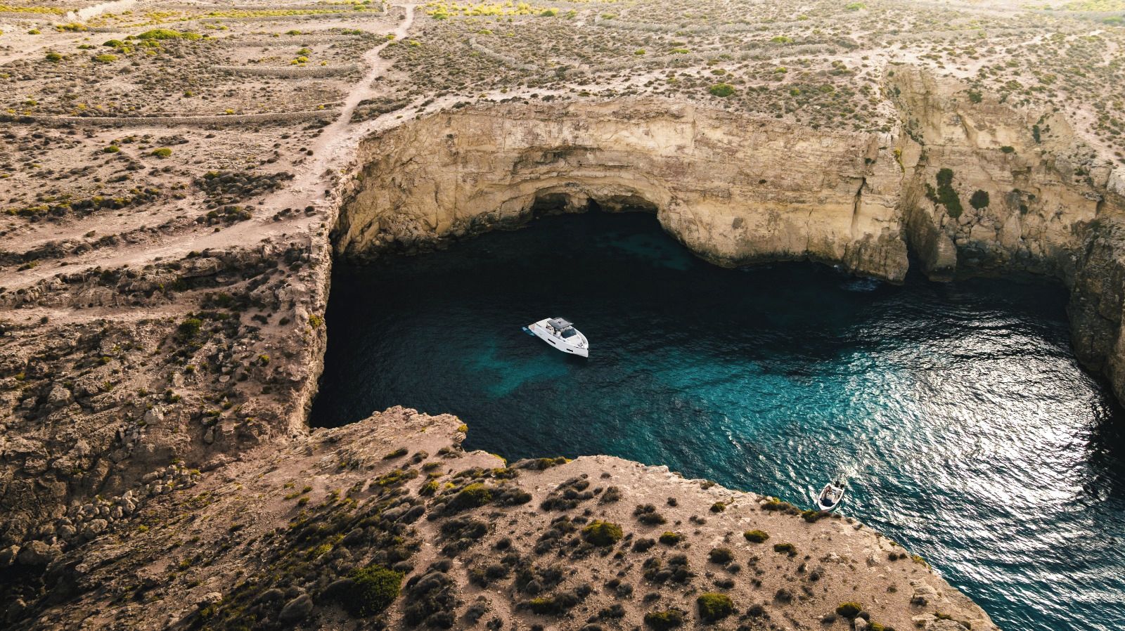 A boat in a natural water body surrounded by rocky terrain.