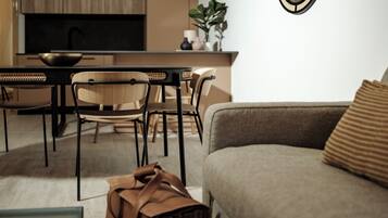 Una sala de estar moderna con un sofá, sillas, una mesa de comedor y una cocina al fondo.