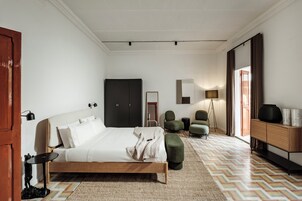 Un dormitorio moderno con una cama de madera, un espejo grande, una lámpara de pie y un sillón verde.