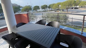 Eine Terrasss mit Tisch und Stühlen mit Blick auf eine Marina, in der Boote liegen, und eine hügelige Landschaft.