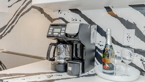 A modern kitchen with a coffee machine, a bottle of champagne, and two glasses on a marble countertop. - Amazing Home Niagara Fall .  (Thorold)