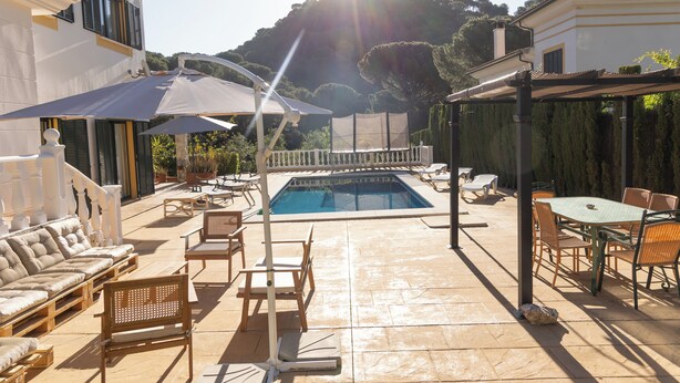 A poolside area with a pool, lounge chairs, and a table with chairs. - Villa Sueños (Córdoba)