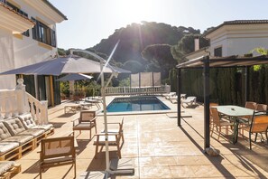 A poolside area with a pool, lounge chairs, and a table with chairs.