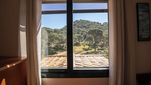 A window with a view of a forested hillside and a tiled roof. - Villa Sueños (Córdoba)