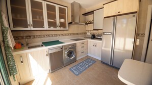 A compact kitchen with a dishwasher, washing machine, and a stainless steel refrigerator. - Villa Sueños (Córdoba)