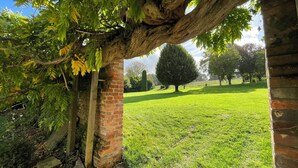 A brick archway with a tree overhanging, leading to a grassy park area with trees and a clear sky. - Eclectic Dorset Country House, Hot Tub, Pool Table, Movie Room,12 guests & pets (Mapperton)