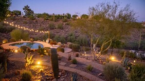 A landscaped garden with a pool, cacti, and a winding path.
