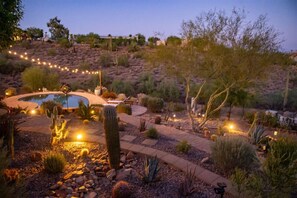 A landscaped garden with a pool, cacti, and a winding path.