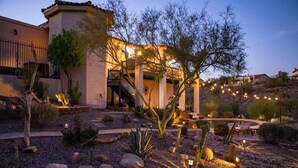 A desert-style building with a patio area, outdoor seating, and string lights.