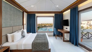 A modern hotel room with a large bed, a desk, a TV, and a view of a swimming pool. - Enrise by Sayaji Dwarka (Dwarka)