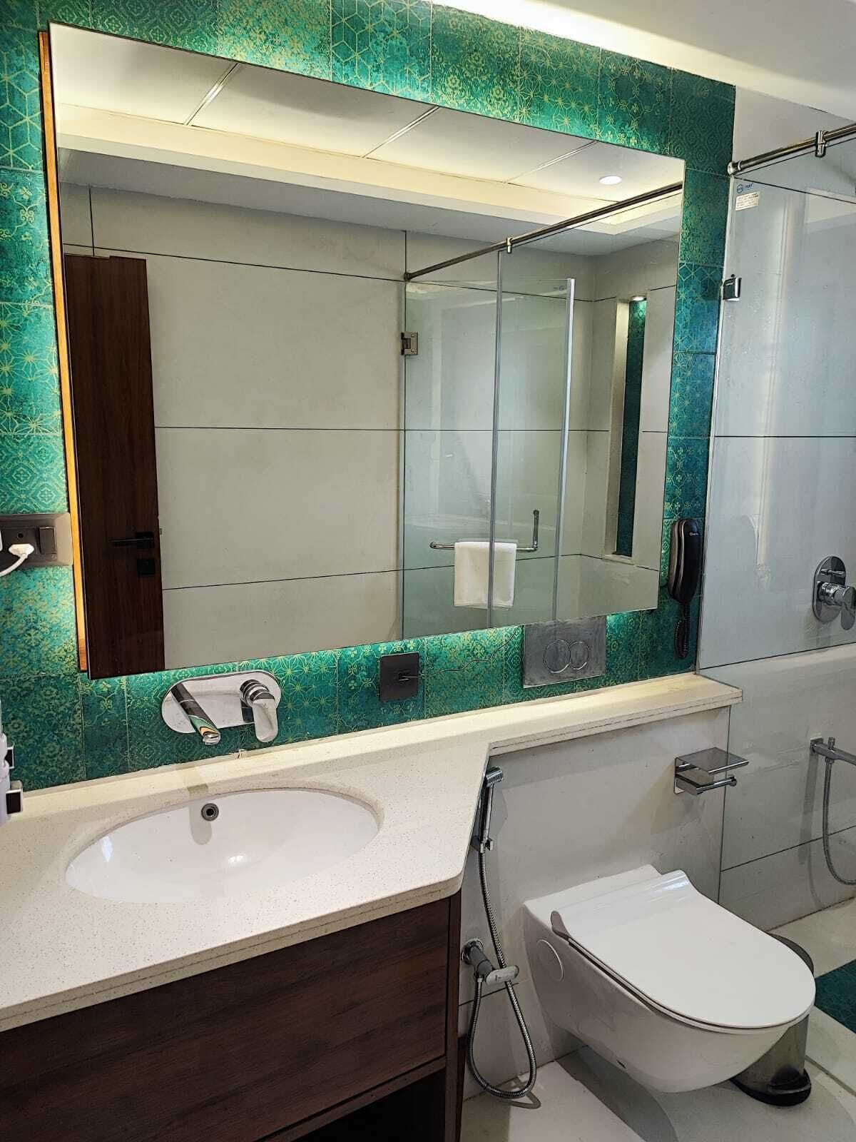 A modern bathroom with a large mirror, a sink, a toilet, and a shower.