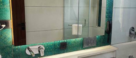 A modern bathroom with a large mirror, a sink, a toilet, and a shower.