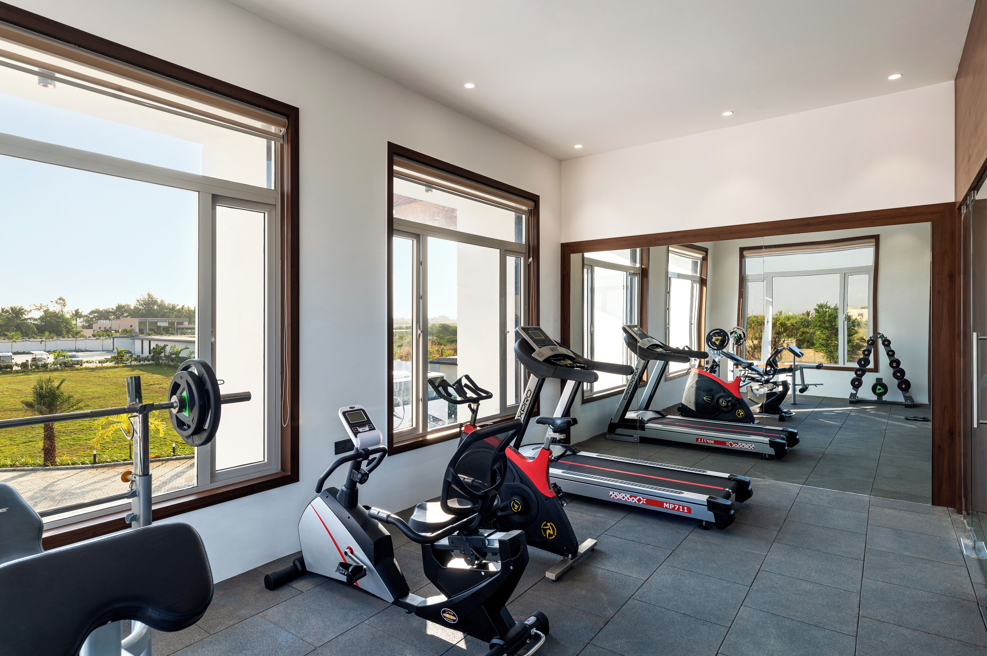 A gym with exercise equipment, large windows, and a view of the outdoors.