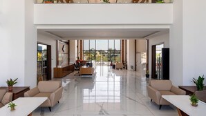 A spacious lobby with a high ceiling, a reception desk, seating area, and large windows offering a view of the outdoors. - Enrise by Sayaji Dwarka (Dwarka)
