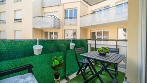 A balcony with a small table and chairs, a potted plant, and a green wall. - Discover the Cocotier Athisien in Athis-Mons, a booming business located 20 minutes from Paris. (Athis-Mons)