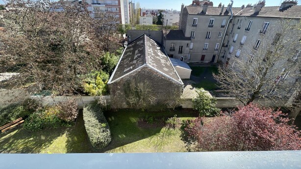Un quartier résidentiel composé d’immeubles d’appartements, d’une petite cour et d’une variété d’arbres et d’arbustes.
